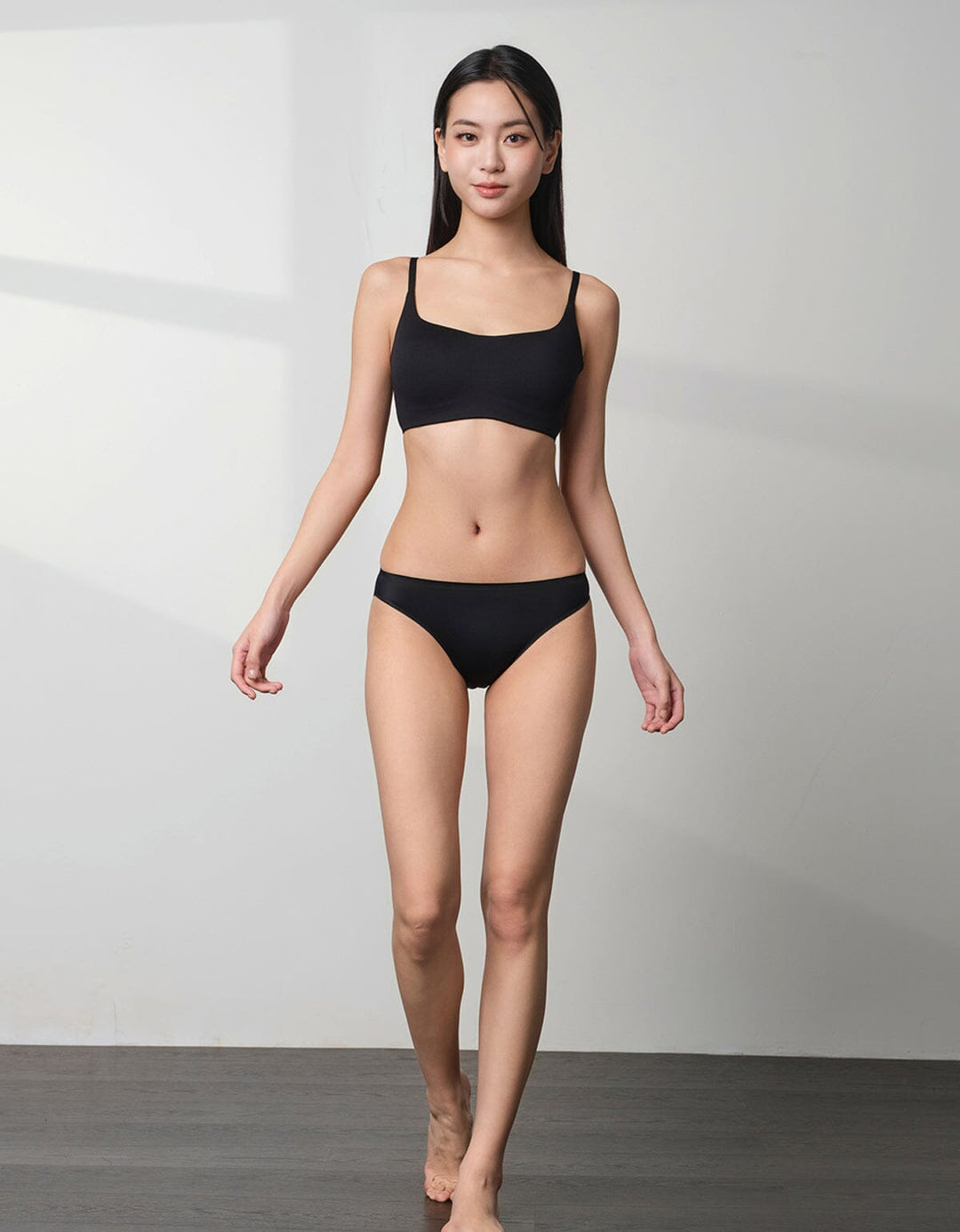 A model is wearing a black SMOOTHING tanga panty